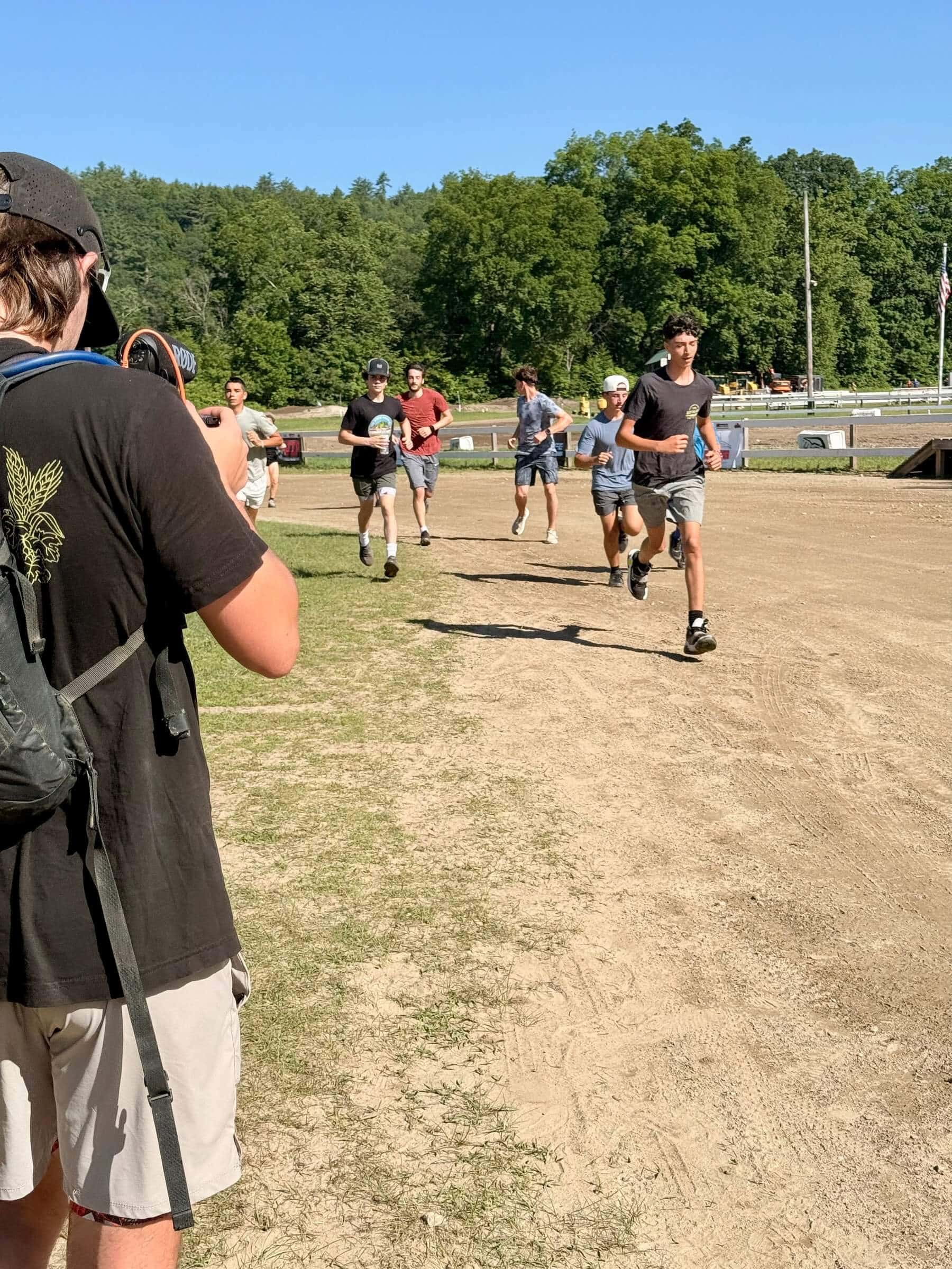 Group of people running on a dirt track with trees in the background
