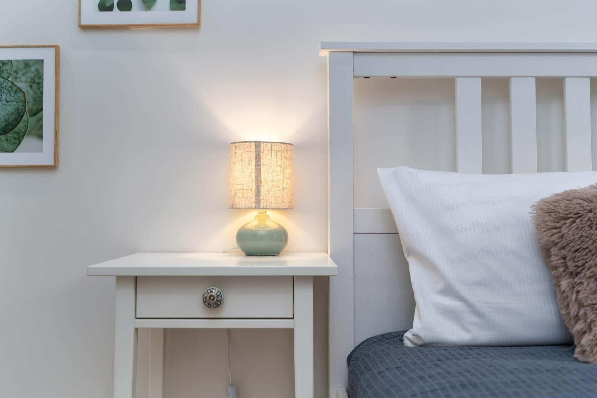 Cozy bedroom with bedside table, lamp, pillows, and bed