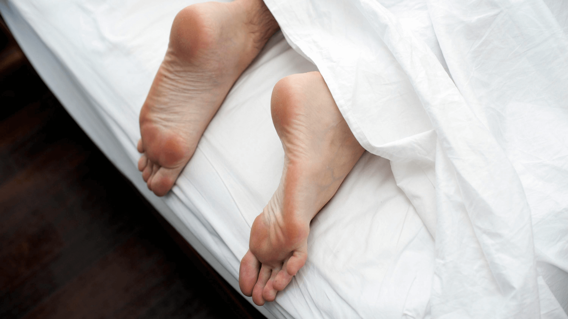 Bare feet peeking out from a cozy blanket, symbolizing the comfort and results of a soft feet routine with GEHWOL Soft Feet care.