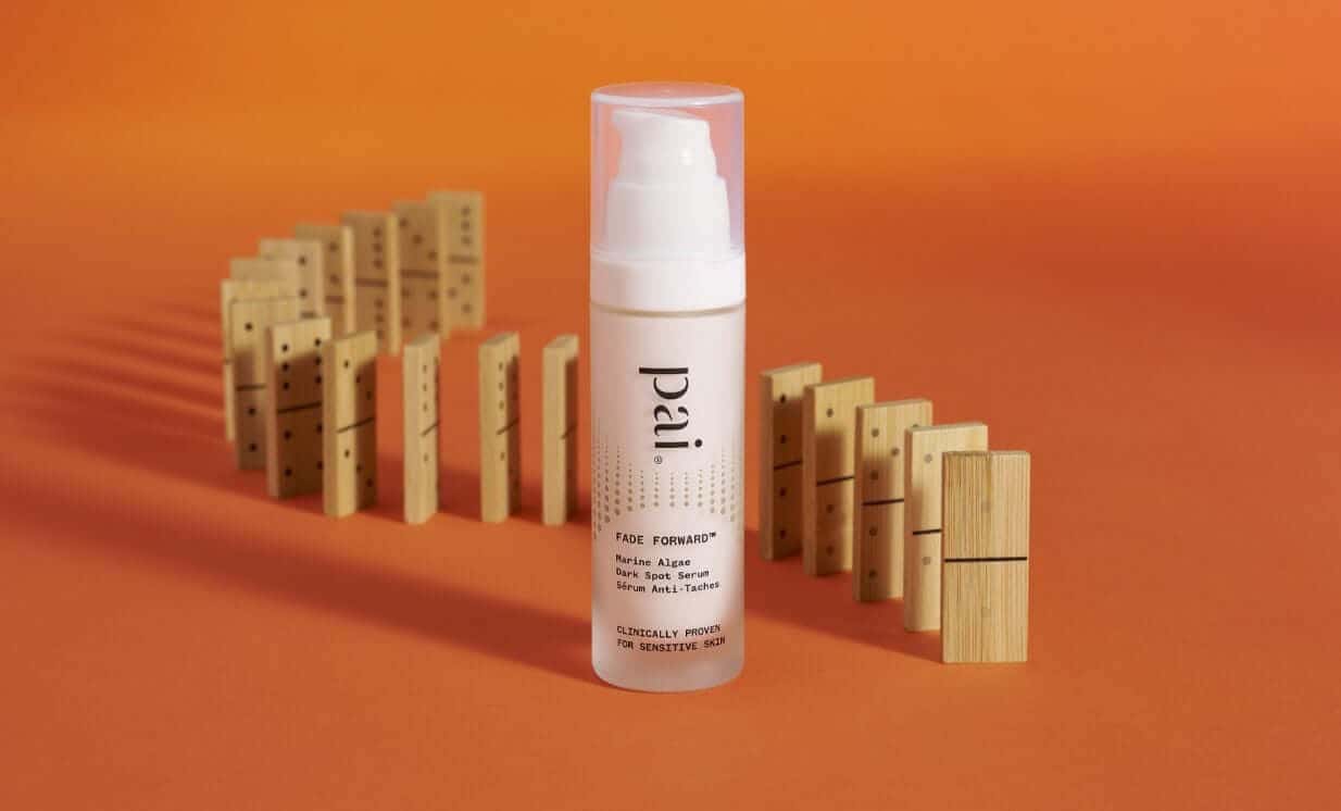 Pai Fade Forward Marine Algae Dark Spot Serum bottle with wooden domino blocks on warm orange background