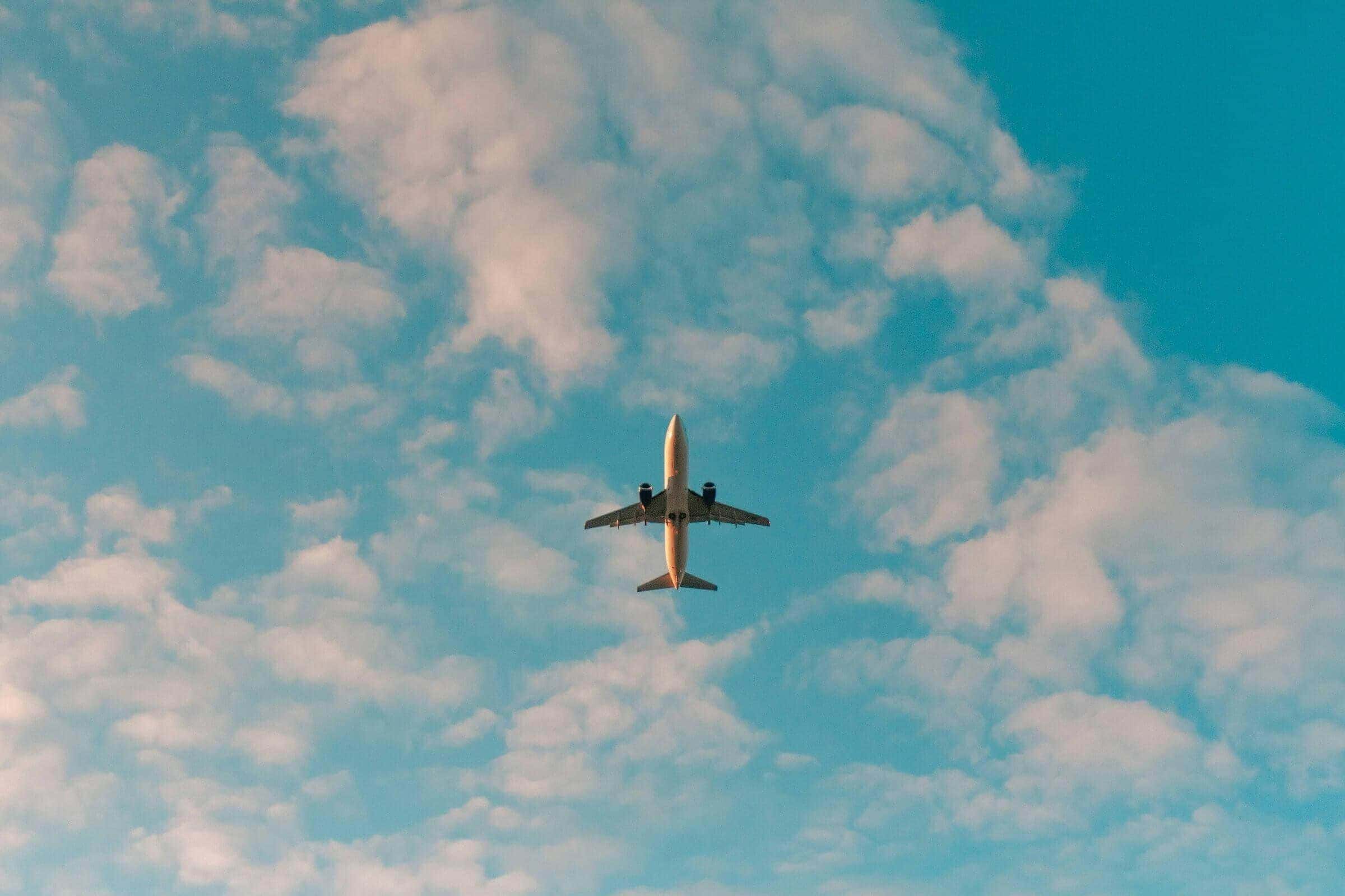 Passenger jet flying overhead against a blue sky with scattered clouds