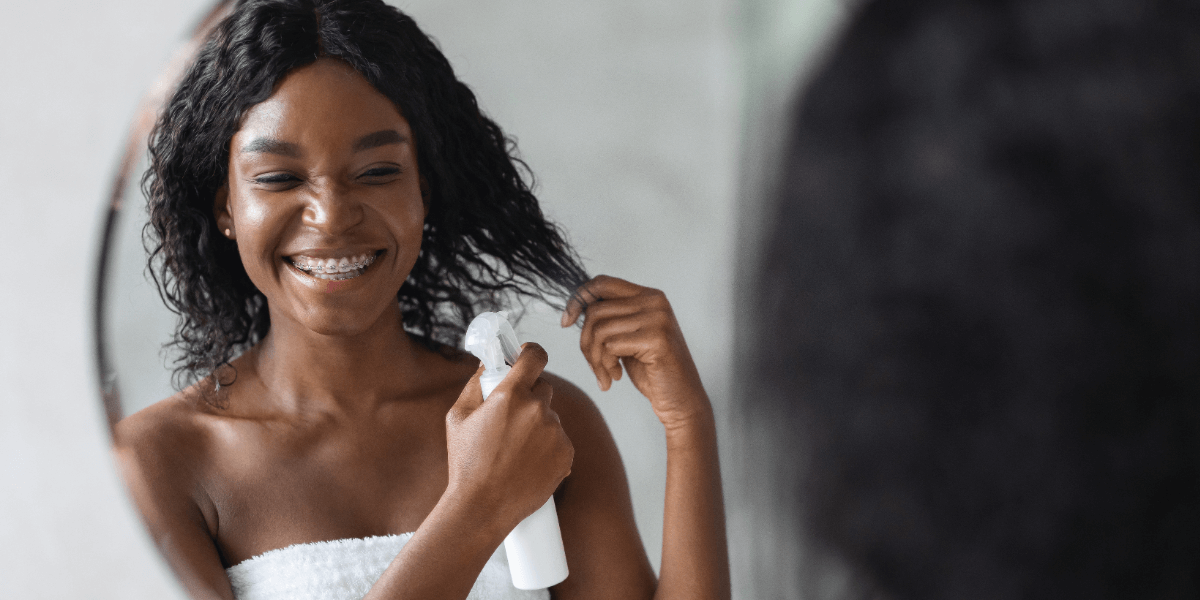 Person holding a section of curly hair in front of a mirror.