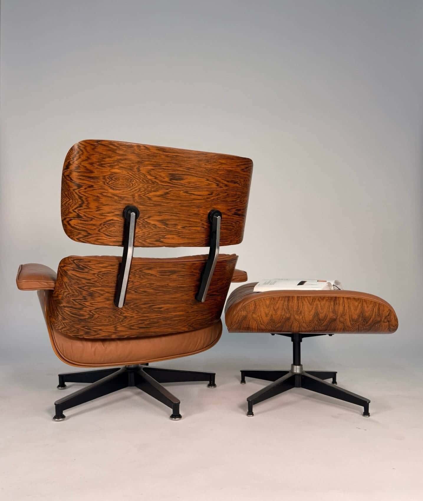 Wooden chair and ottoman with black base on a gray background