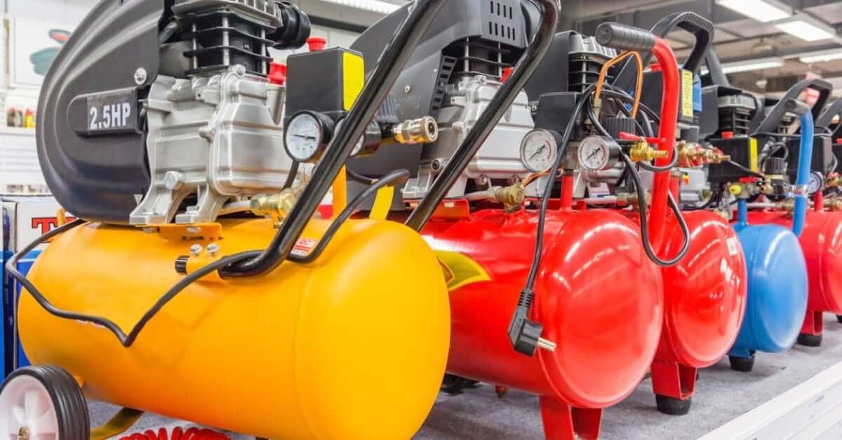 Various colored horizontal air compressor tanks, including yellow, red, and blue, lined up in a warehouse.