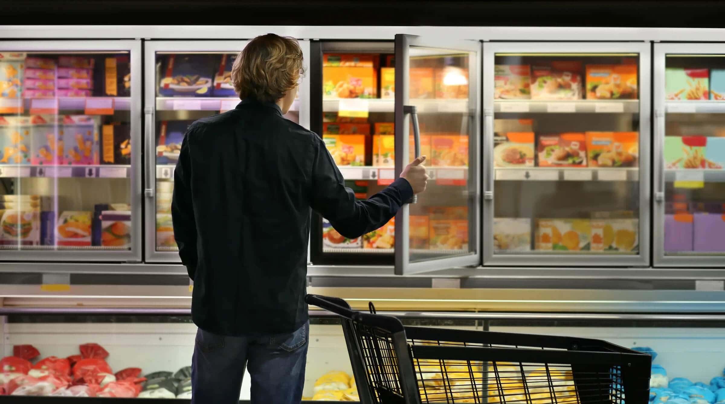 frozen healthy meals displayed in grocery store freezer aisle with shopper opening door to select packaged meals