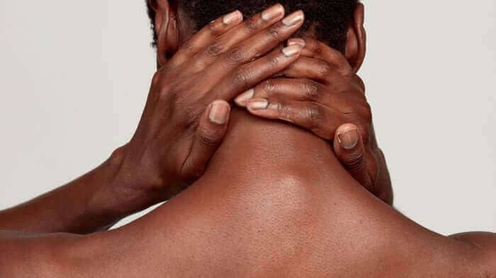 Hands gently massaging the back of neck and shoulders, demonstrating gentle skincare routine for sensitive skin