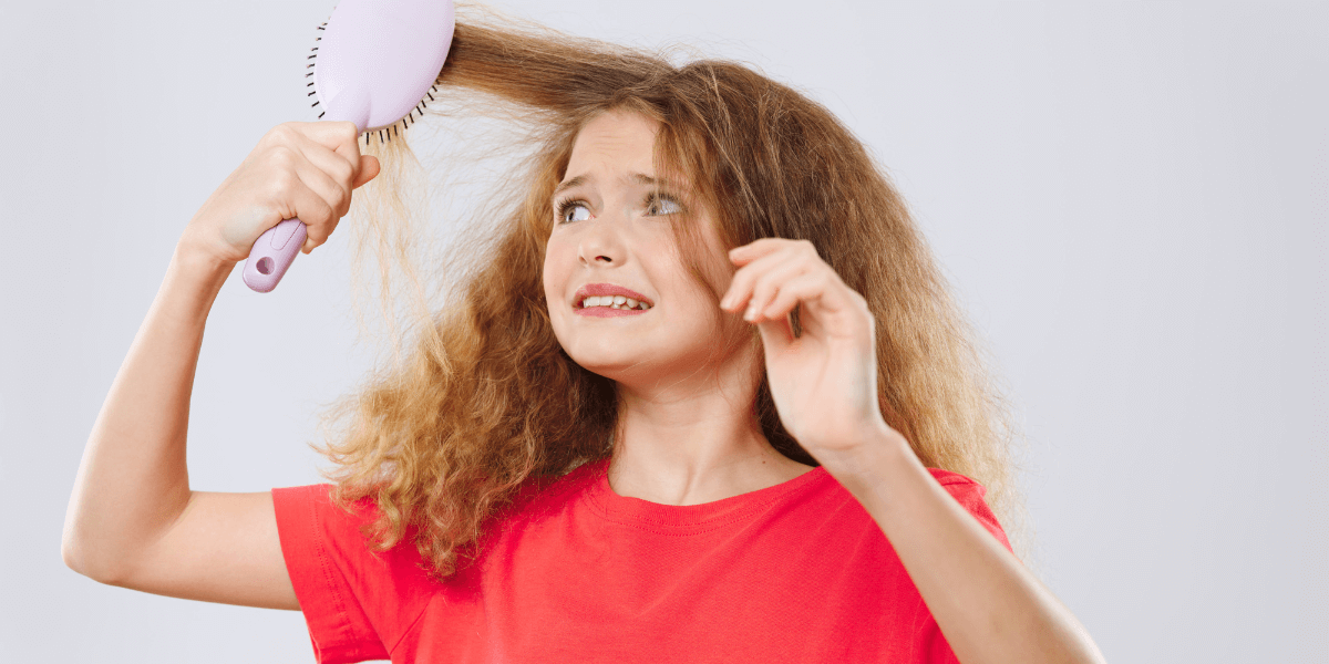 Child using a brush on a tangled section of hair.