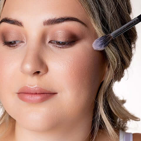 Highlighter being applied to model's cheek area.