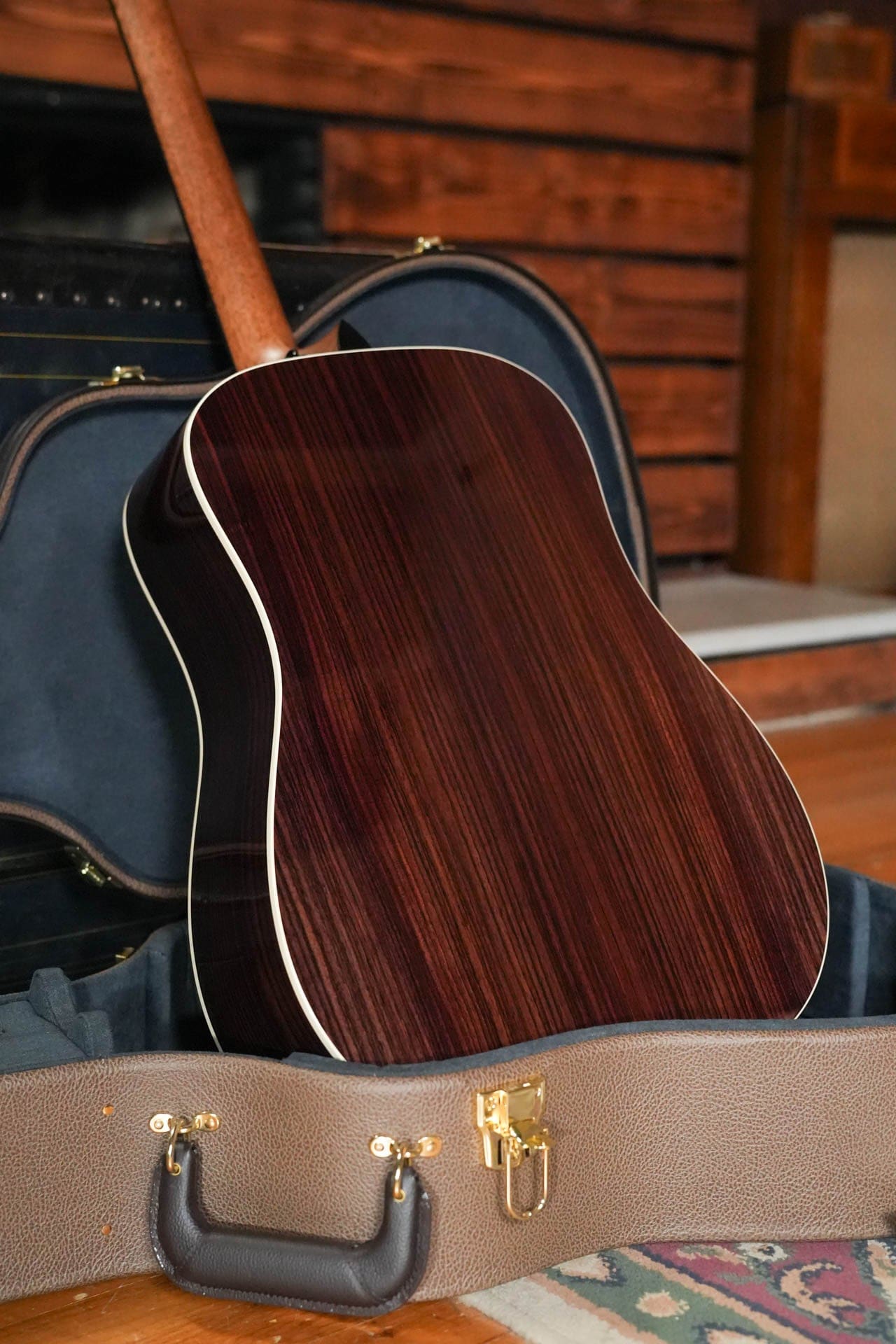 Solid Indian rosewood back of the Taylor Gold Label 710e with cream binding, standing in its open case