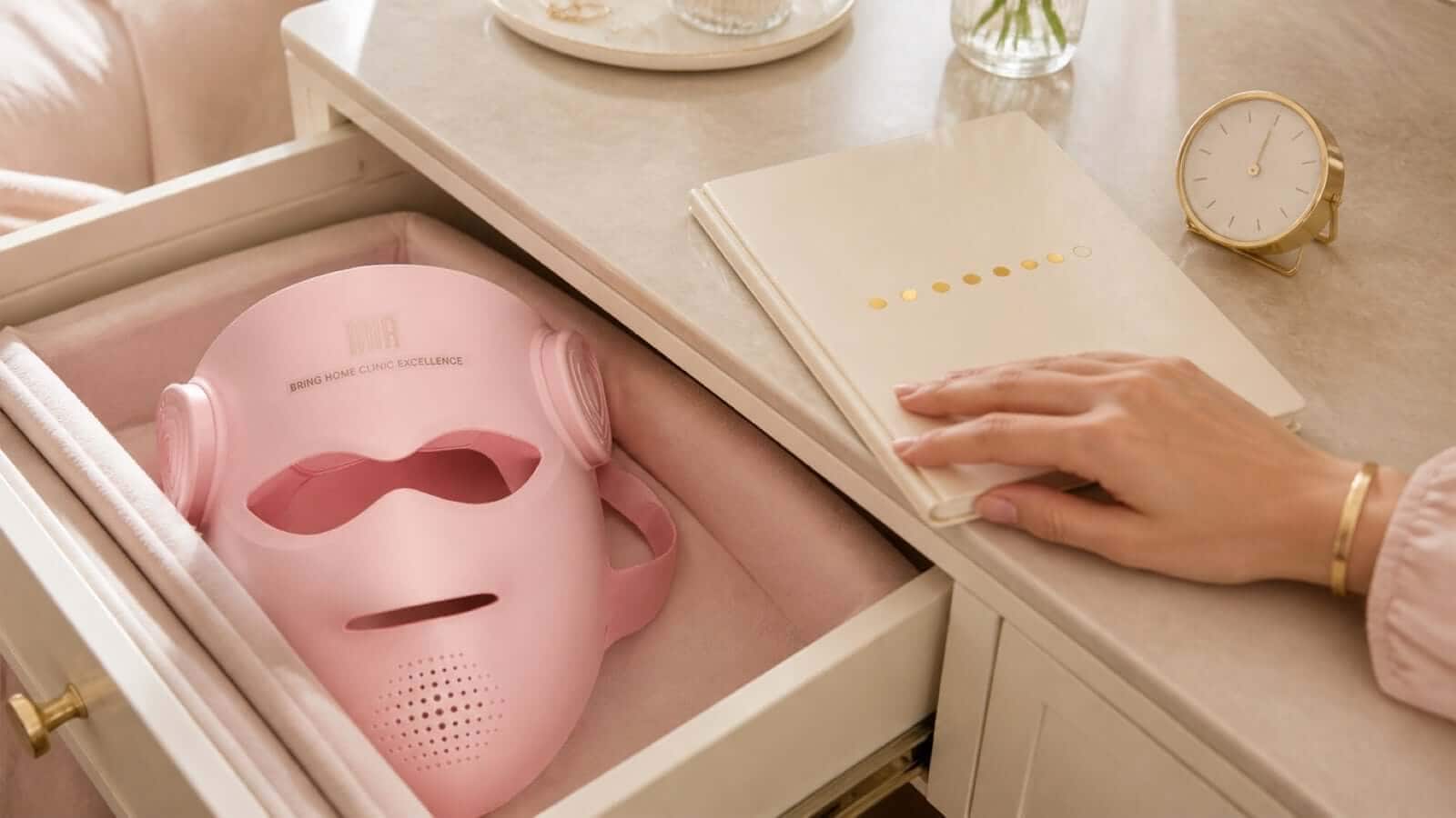 Pink INIA GLOW 4D mask beside a notebook used to track weekly sessions