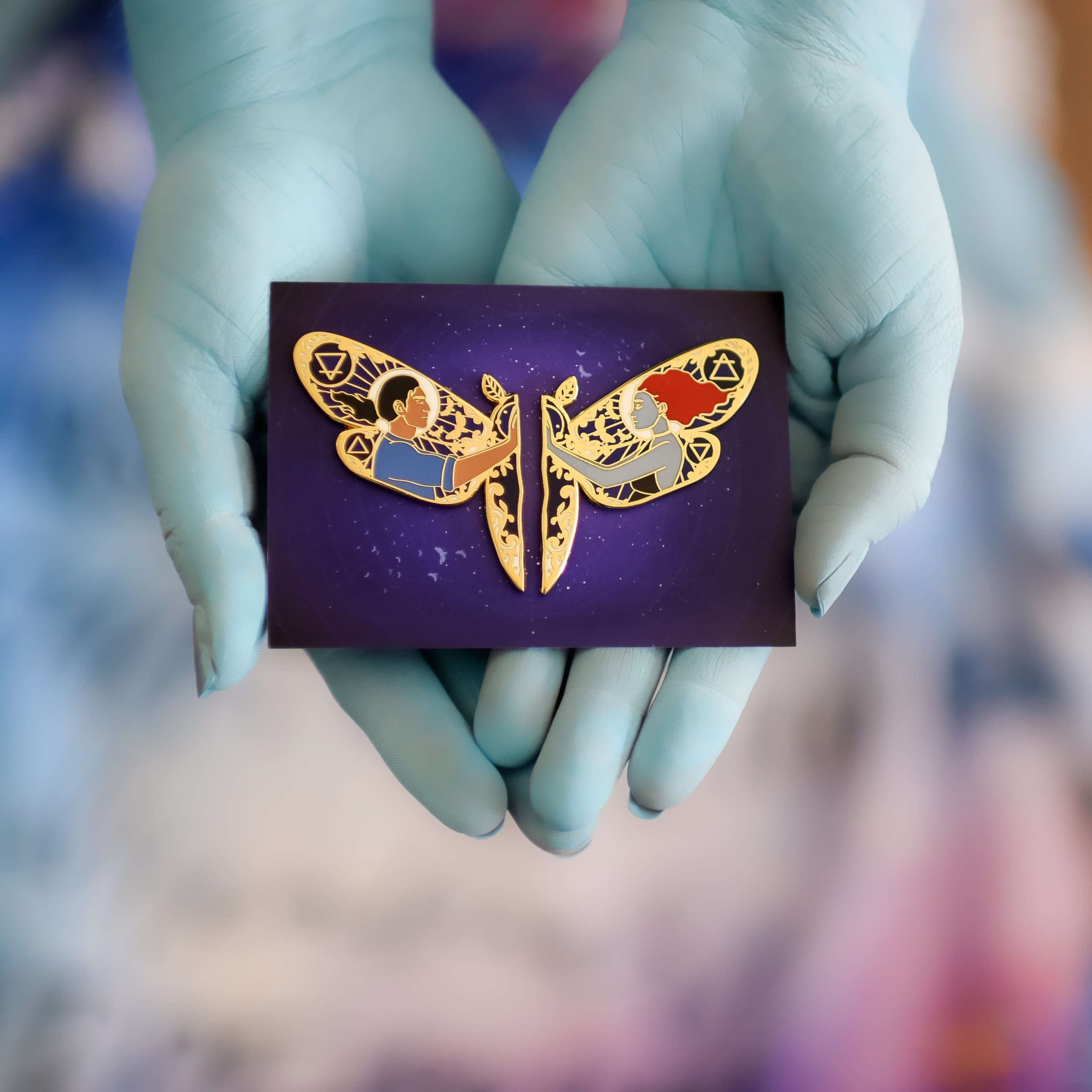 Moth-shaped Lazlo and Sarai Pin Set with one character from Strange the Dreamer on each side of the 2-piece set