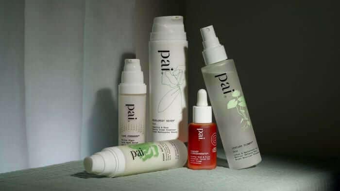Pai Skincare evening routine products on mint green surface including cleansers, rosehip oil serum and moisturizers for nighttime skincare