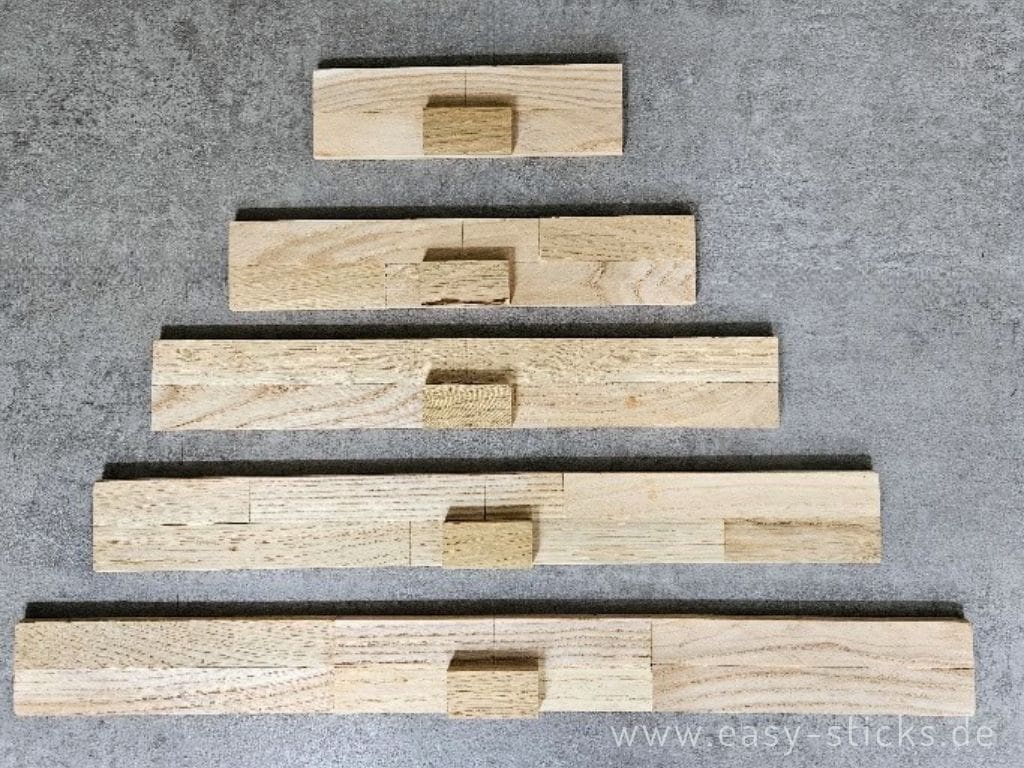 Die kleinen Holzklötzchen werden mittig auf die Bretter geklebt