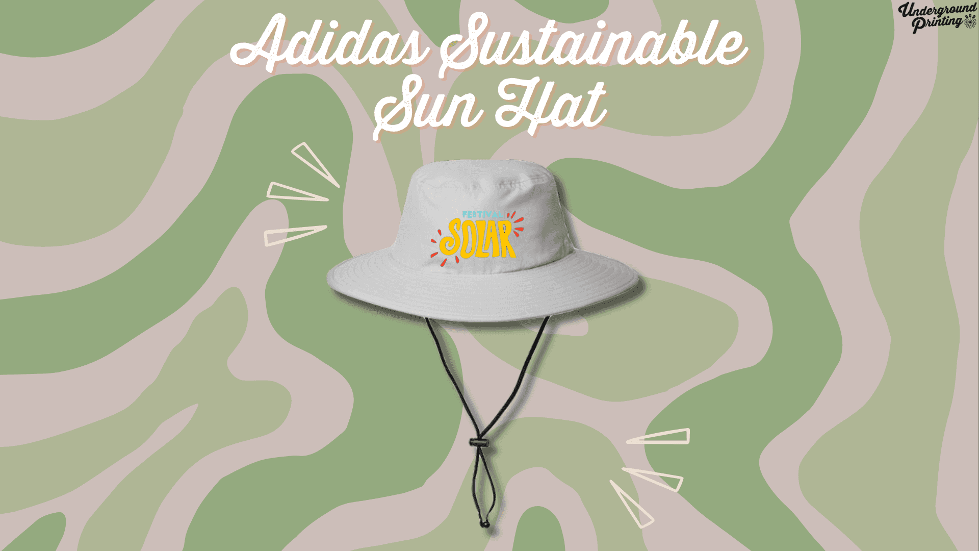 A light gray sun hat with a wide brim, featuring a custom "Festival Solar" logo in bright colors. The hat has an adjustable chin strap and is displayed against a green and beige camouflage-style background with accent lines around it.