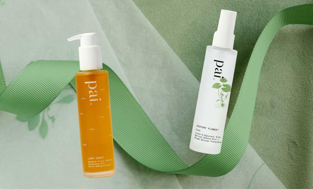 Pai Skincare Light Work Rosehip Cleansing Oil and Century Flower Toner arranged with green ribbon on sage background