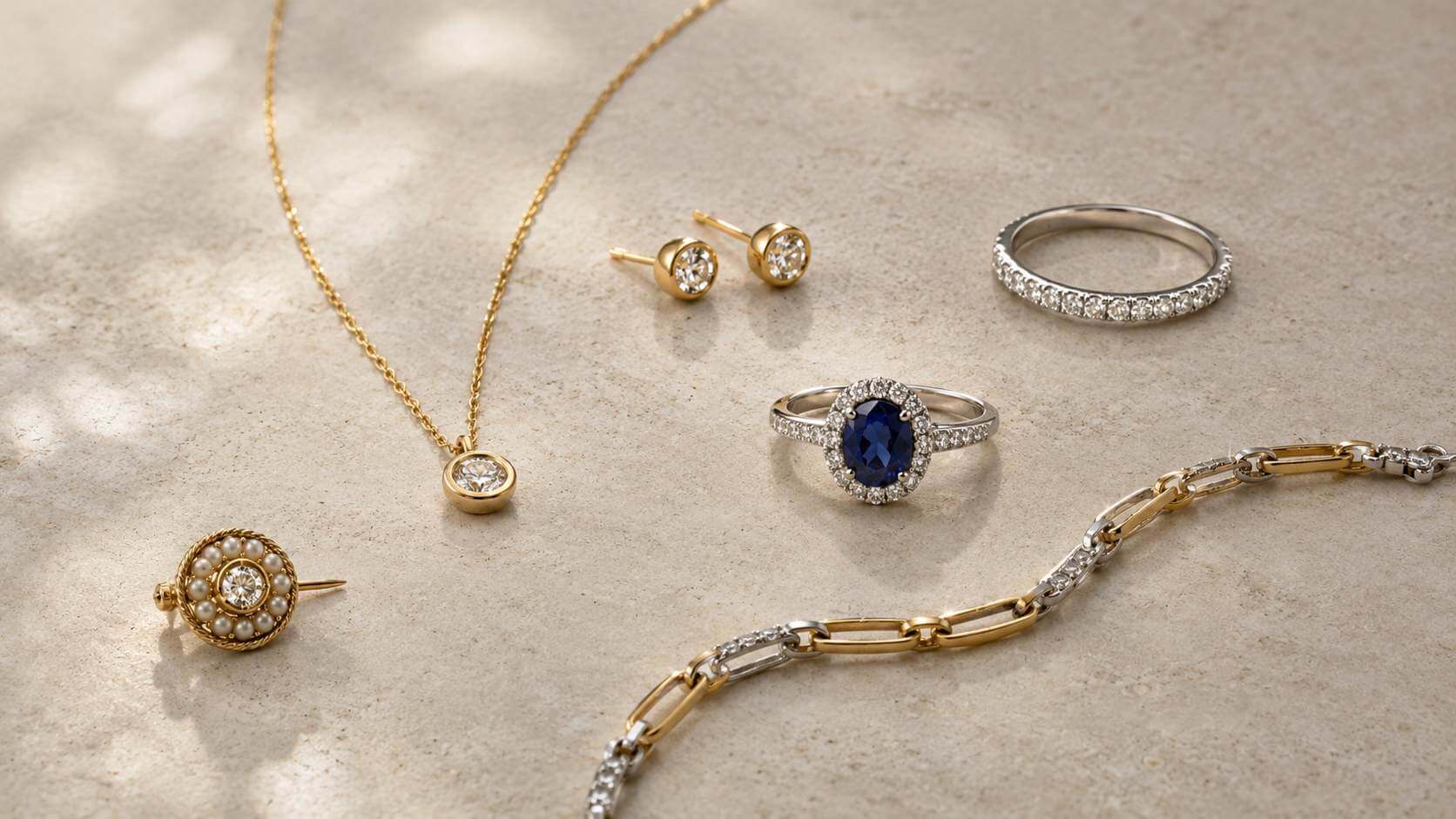 Mixed yellow-gold and white-gold diamond jewellery arranged with a blue sapphire ring in a visually balanced edit.