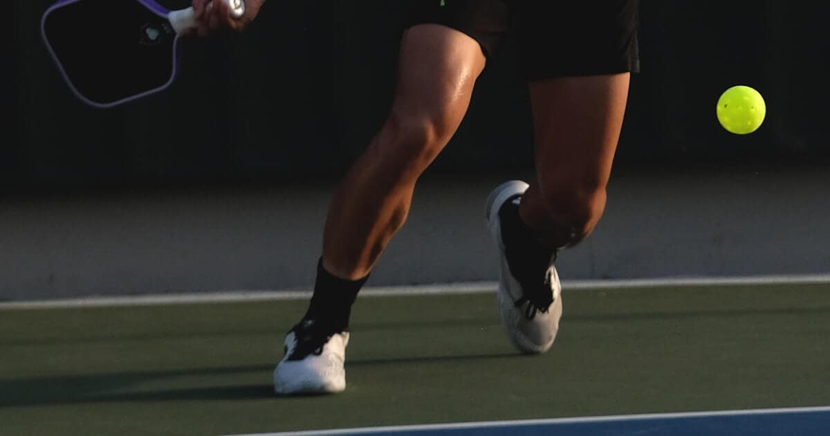 A senior pickleball player swinging one of the best pickleball paddles for seniors on an outdoor court.
