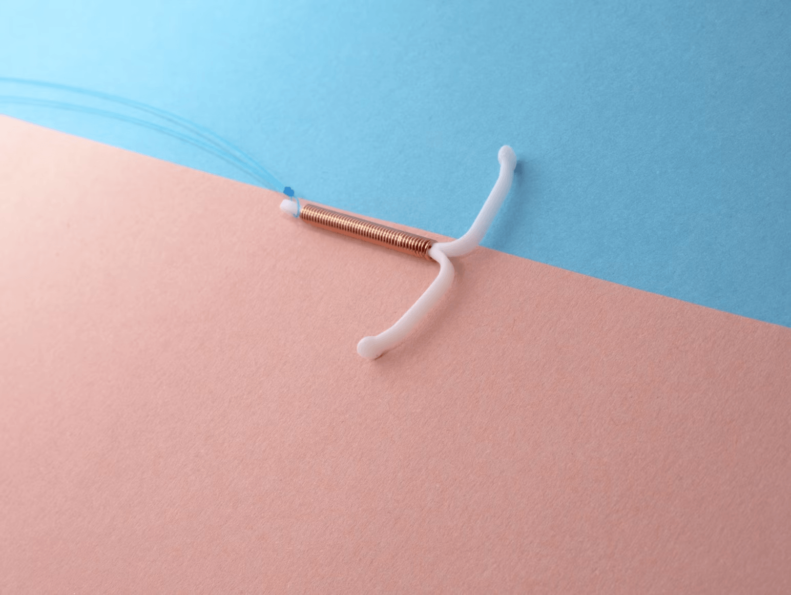 Copper IUD on pastel colored background