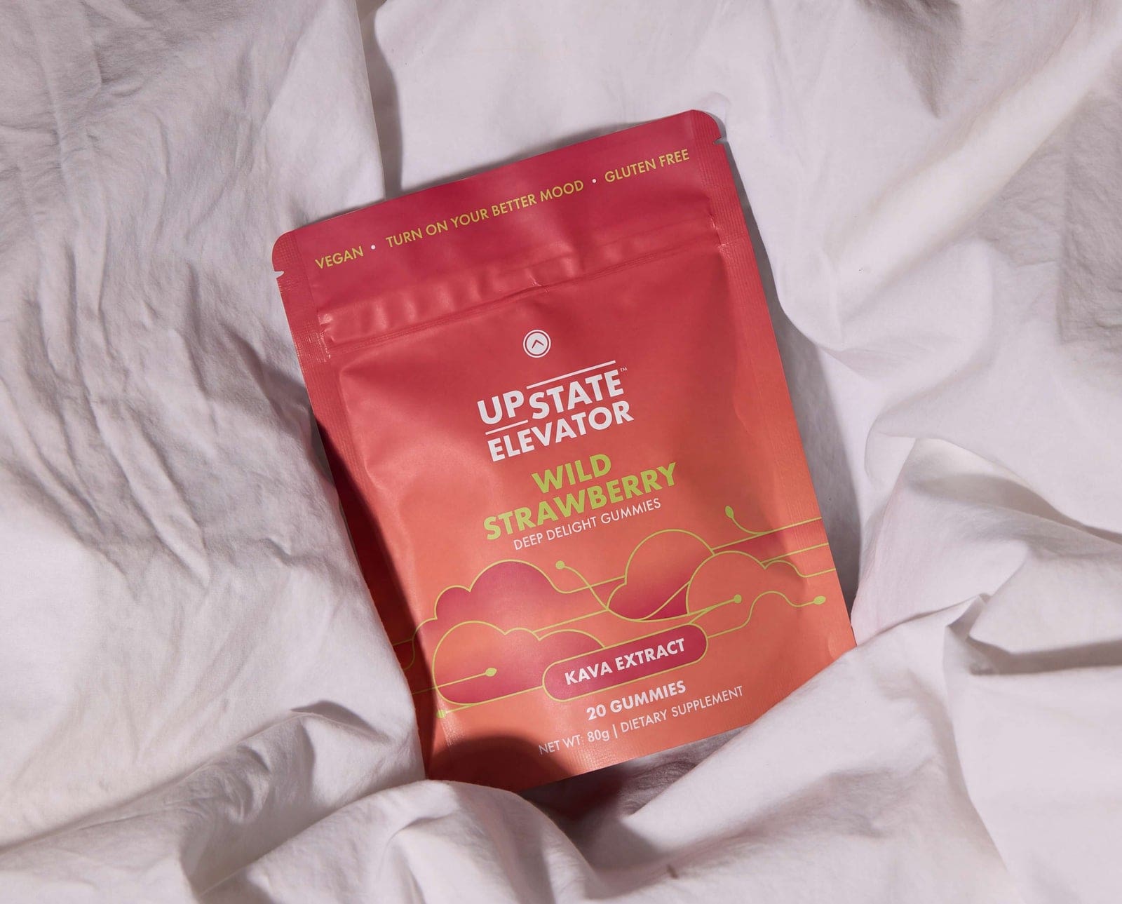 An Upstate Elevator Wild Strawberry Deep Delight kava gummies pouch resting on white bed linens.