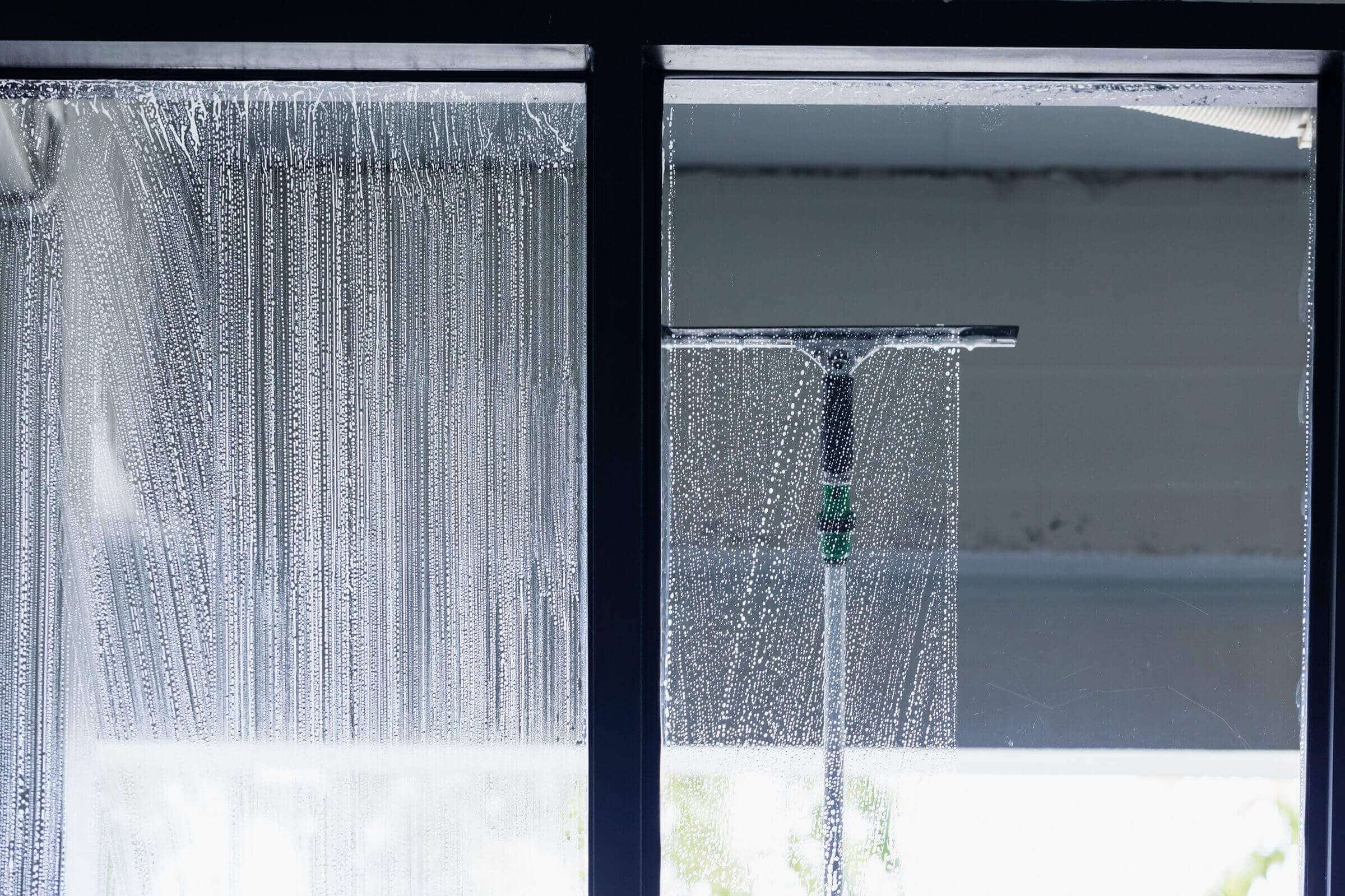 Professional window cleaner using a squeegee on a storefront window
