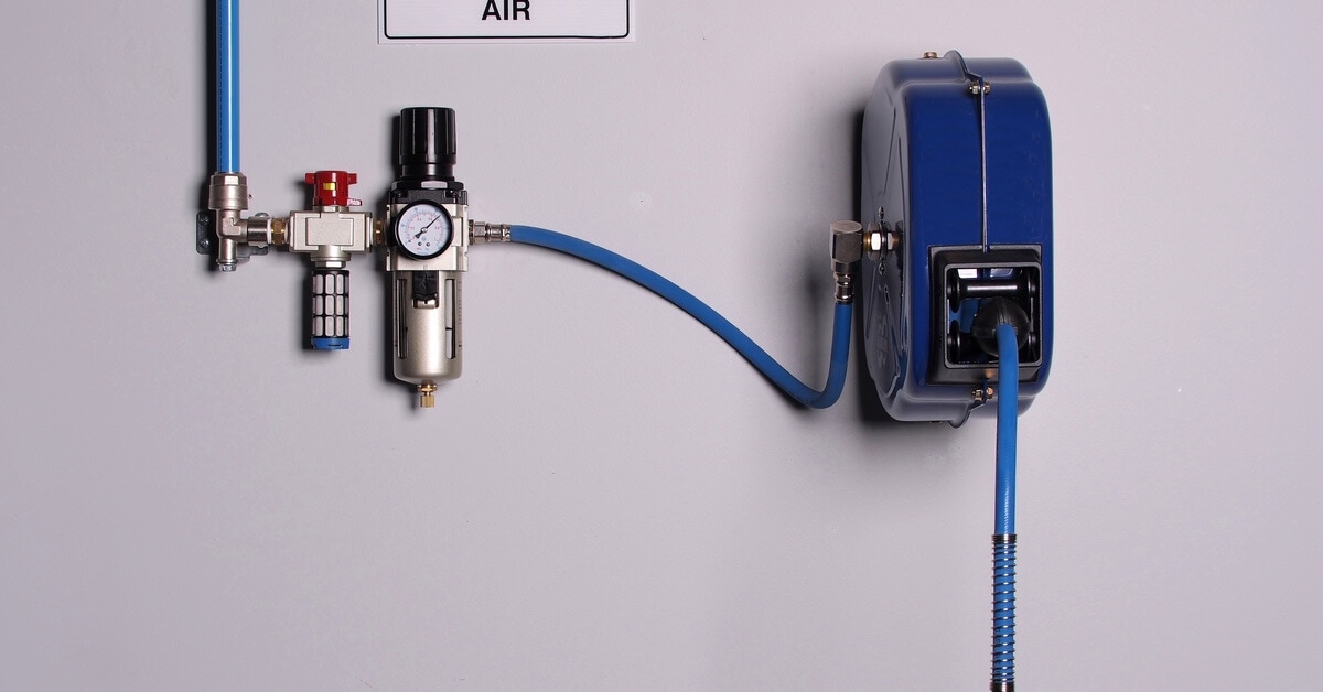 A compressed air system with blue pipes, a filter, a pressure gauge, a hose reel, and a 