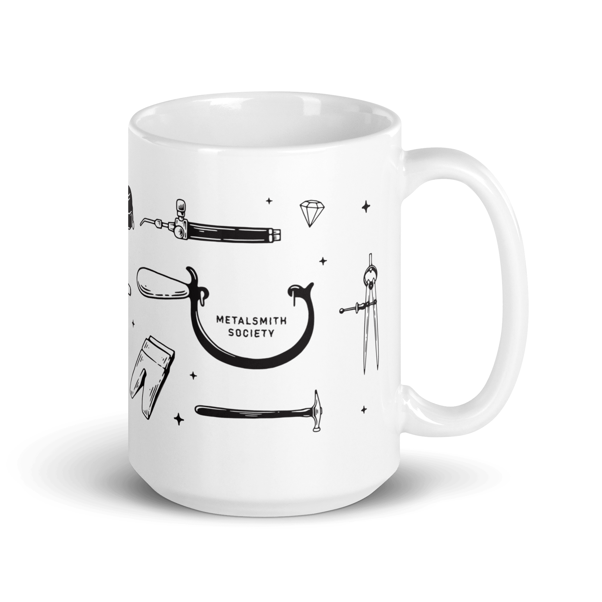 White Metalsmith Society Mug with jewelry making tools including a saw frame, calipers, a bench pin, a torch head and a jeweler's hammer. The mug is on a white background.