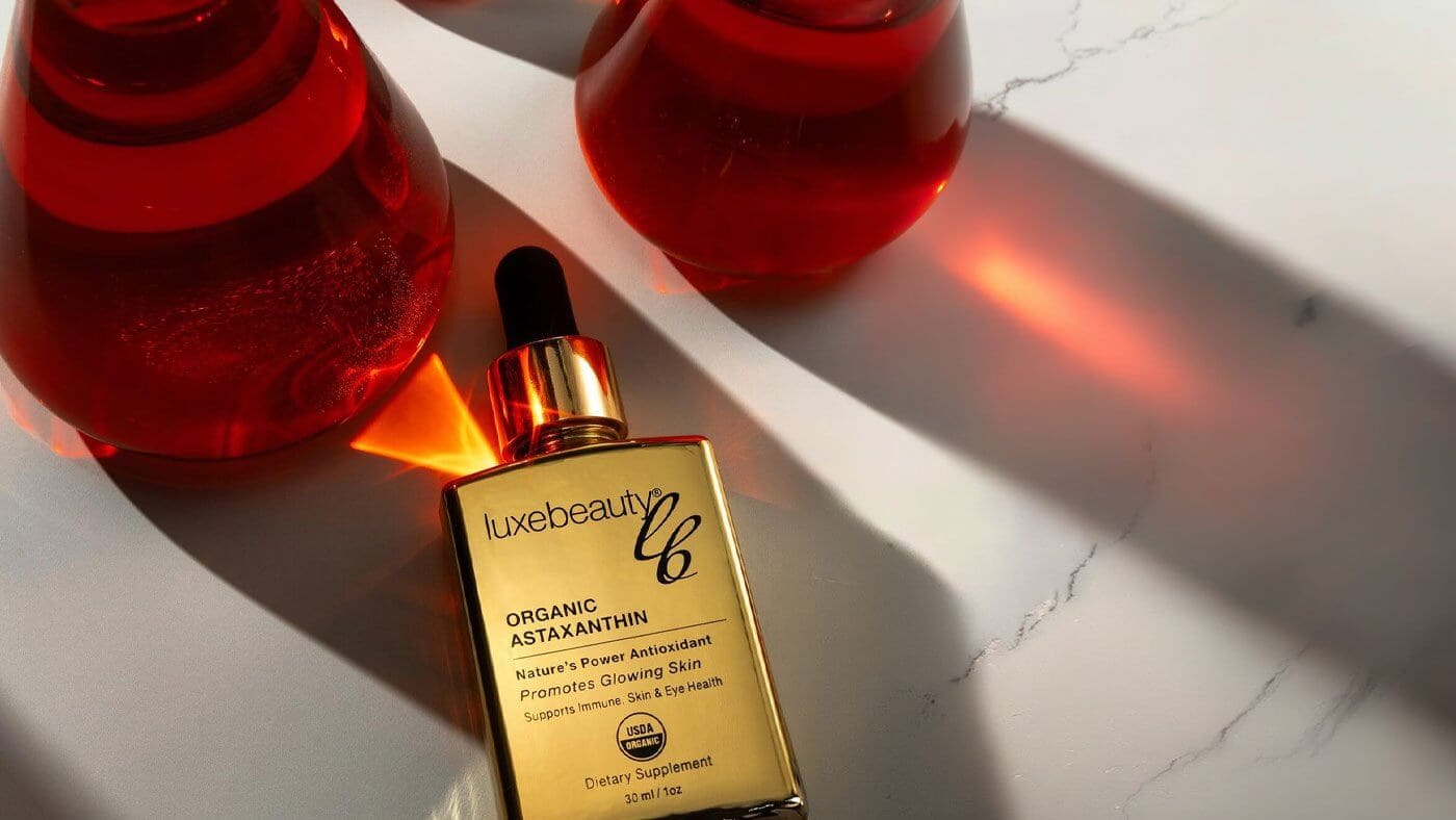Best astaxanthin supplement by Luxe Beauty shown with laboratory glass beakers highlighting certified organic purity and antioxidant potency