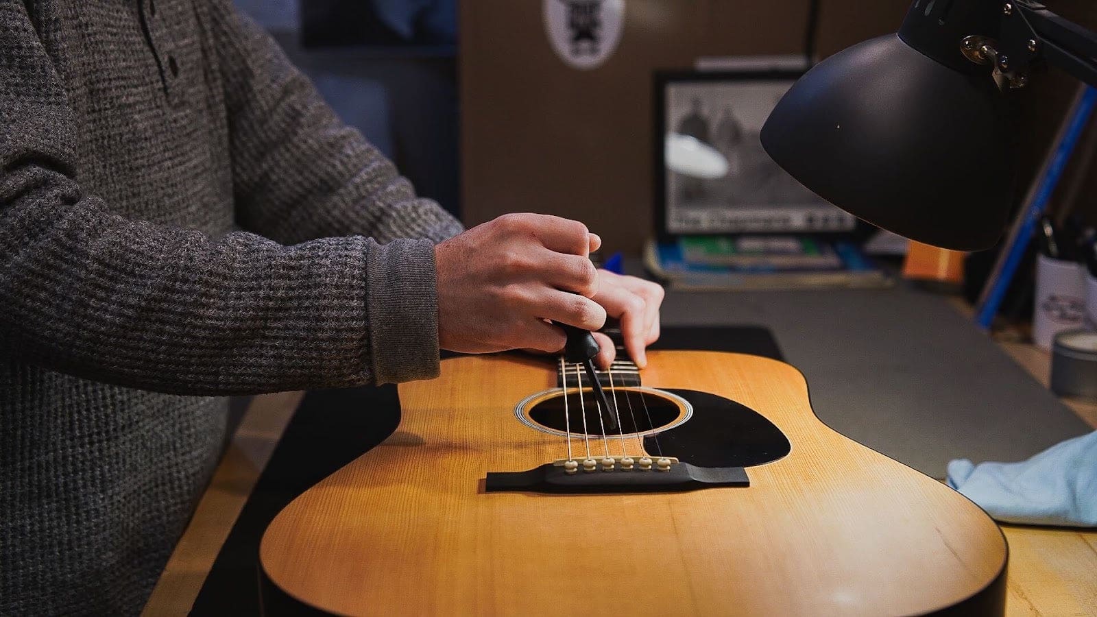 Technician working at the soundhole of a spruce-top dreadnought during an inspection