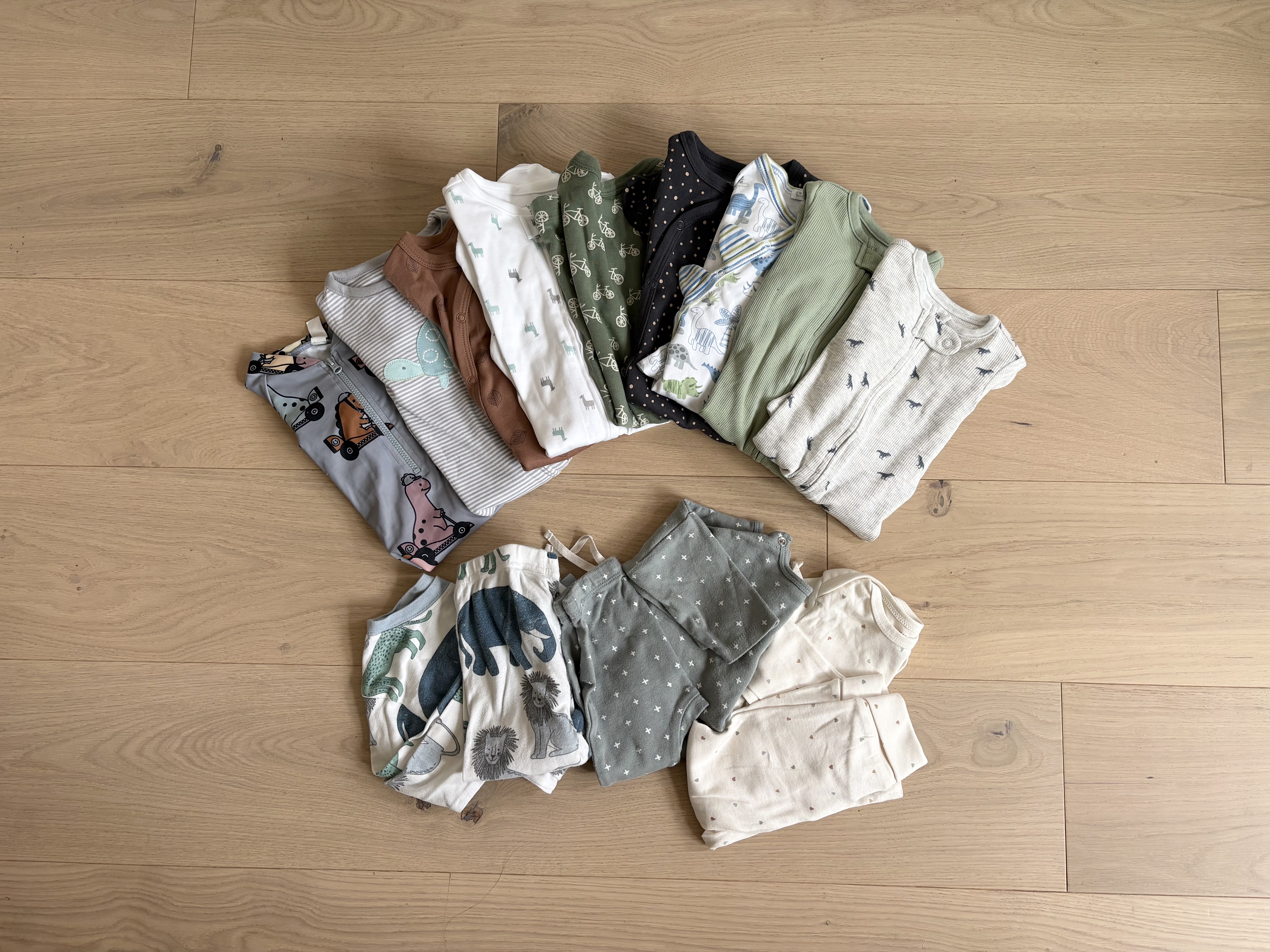 	Nine folded baby outfits and three matching two-piece pajama sets laid out for a week-long trip