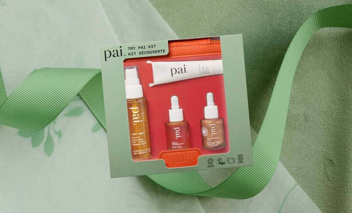 Pai Try Pai Kit skincare gift set with travel-size cleanser and serums, surrounded by green ribbon on textured background