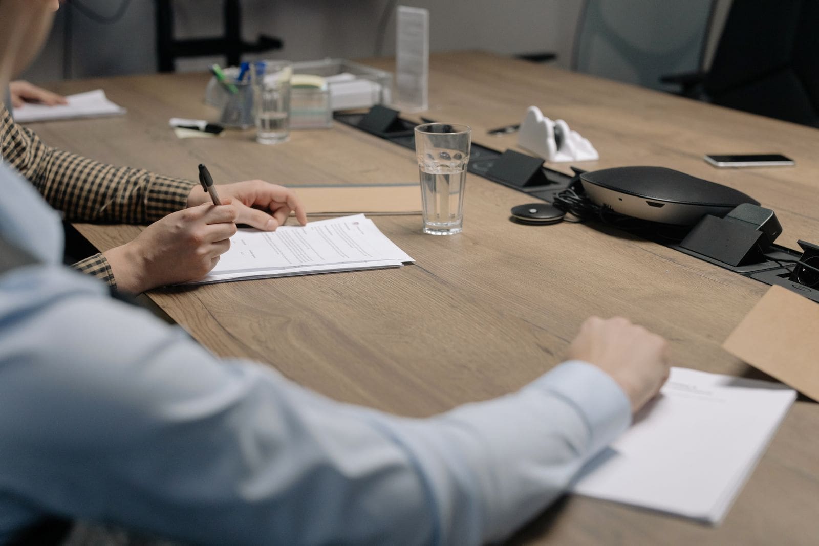 Two people reviewing printed documentation across a conference table, the kind of paperwork that accompanies an audio chain of custody file