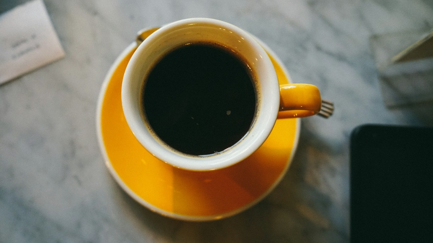 Black coffee in yellow ceramic cup.