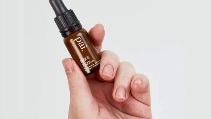 Hand holding Pai Skincare Prebiotic Inulin 4% Protective Booster against clean white background