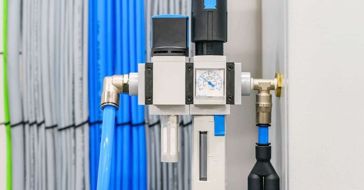 A combination unit for a pneumatic air filter and pressure regulator with a check valve and wiring in the background.