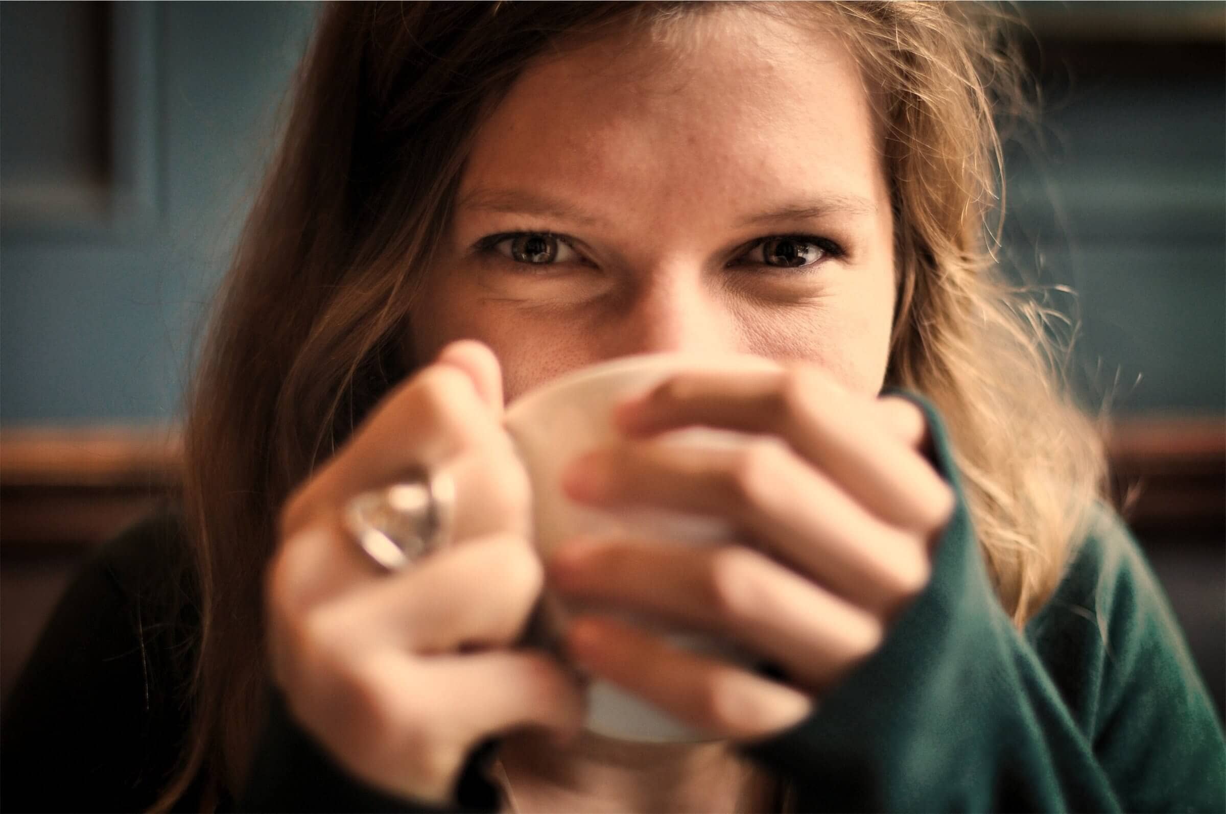 Woman smiling while drinking from cup.