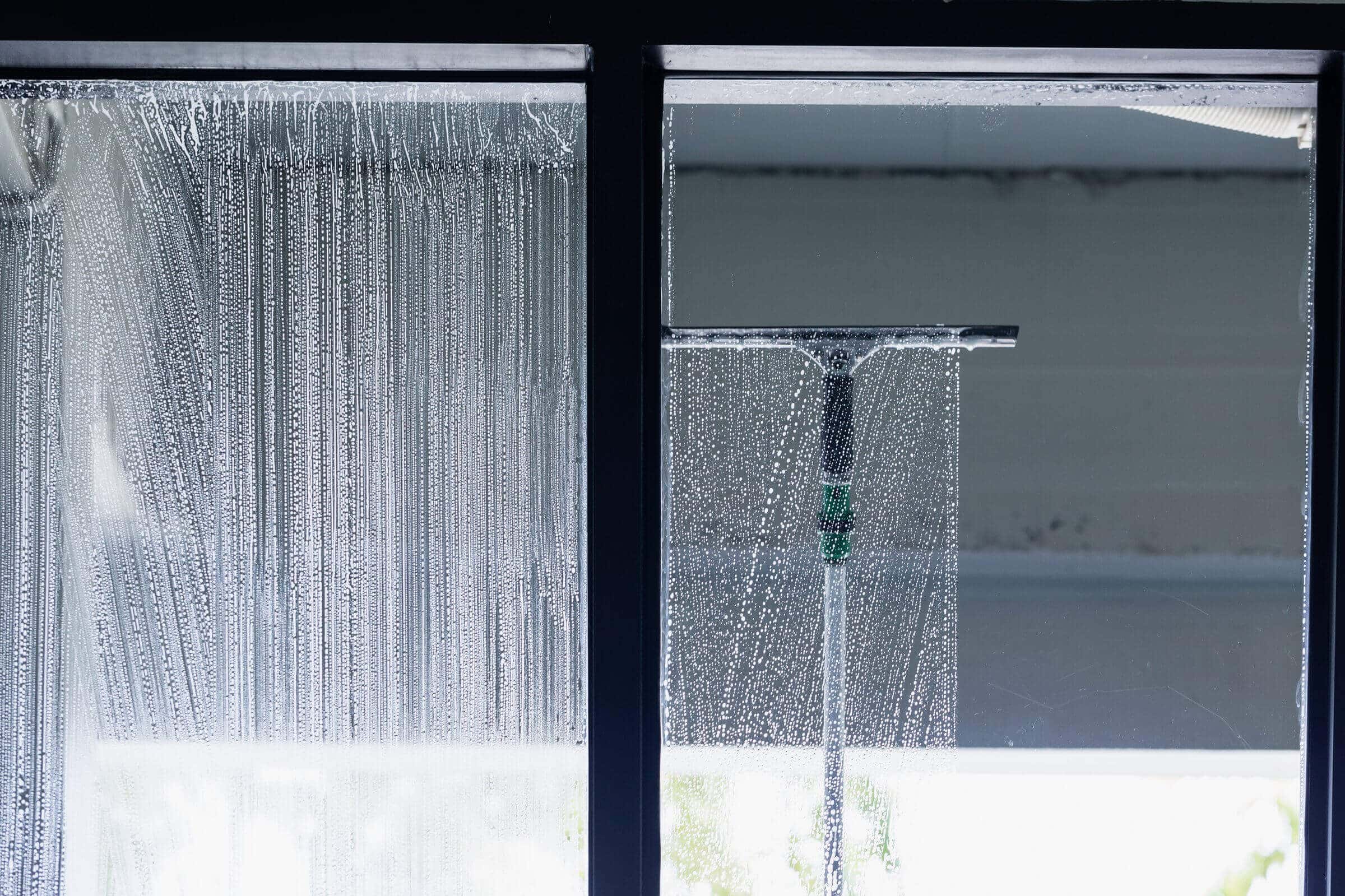 Professional window cleaner using a squeegee on a storefront window