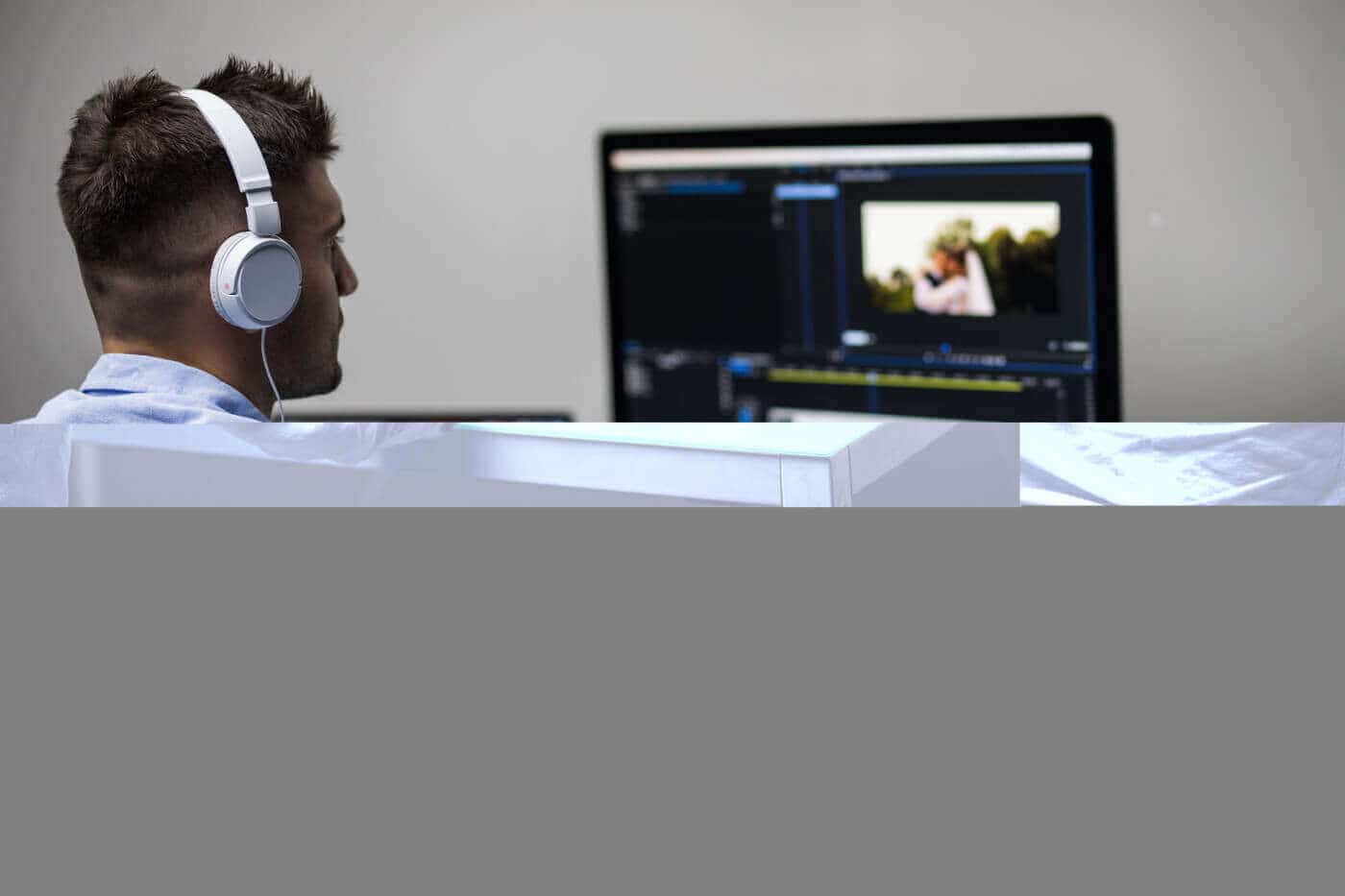 Editor working at a monitor with headphones, representing video project tracking in Trello