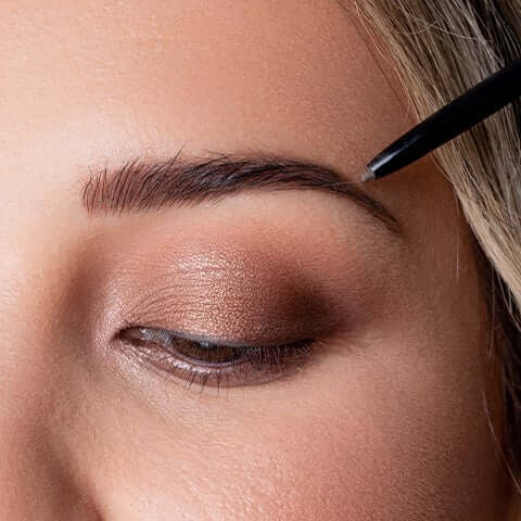 Eyebrow pencil being applied on eye brow of model.