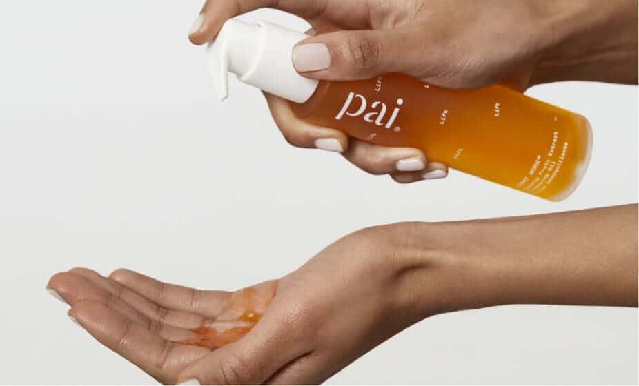 Woman dispensing Pai Light Work Rosehip Cleansing Oil into palm, showing golden cleansing oil texture
