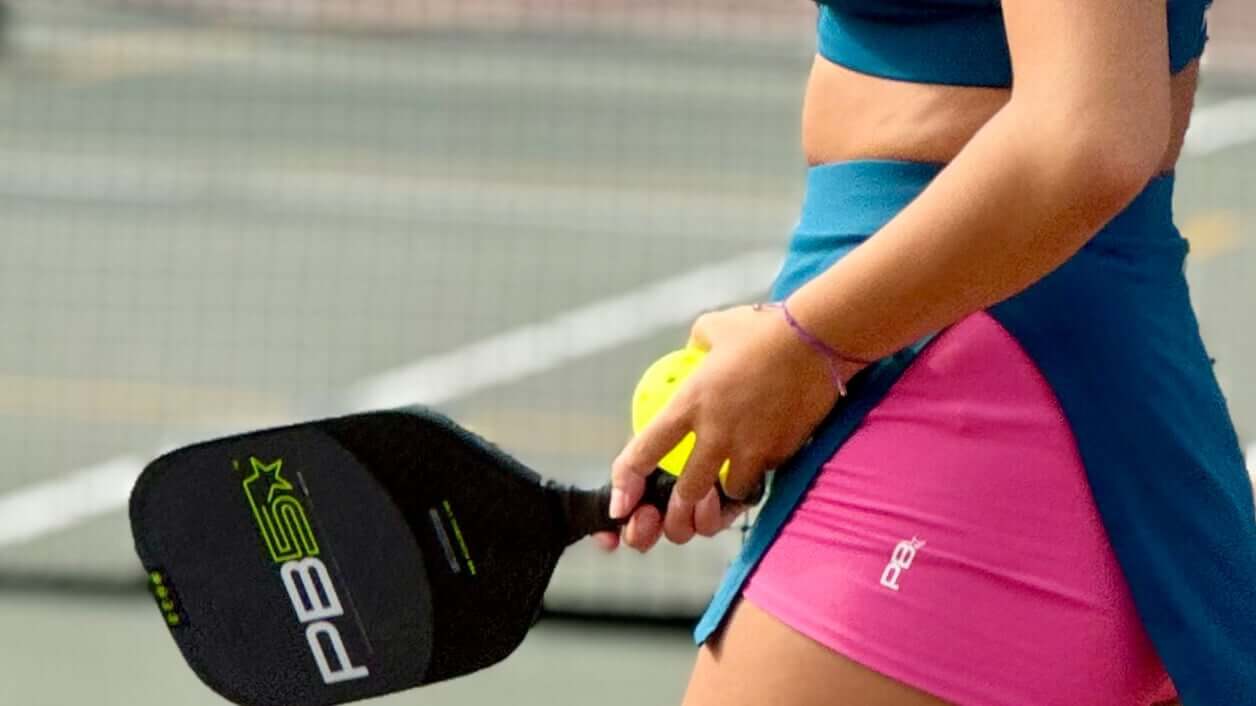 Pickleball player holding a paddle and ball