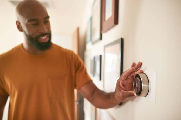 Man Turning the Air Conditioning Thermostat Up