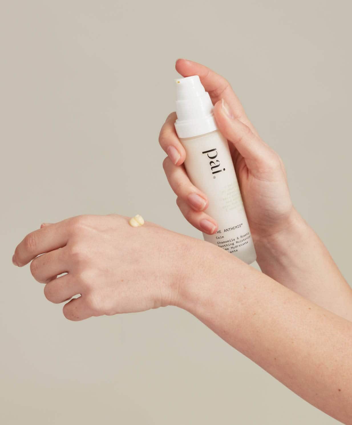 Hands gently holding Pai Chamomile & Rosehip Calming Day Cream with small amount dispensed, showing gentle skincare for sensitive rosacea-prone skin