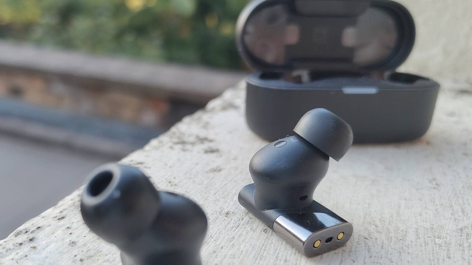 Status Audio Pro X earbuds resting on a window sill, showcasing their sleek design.