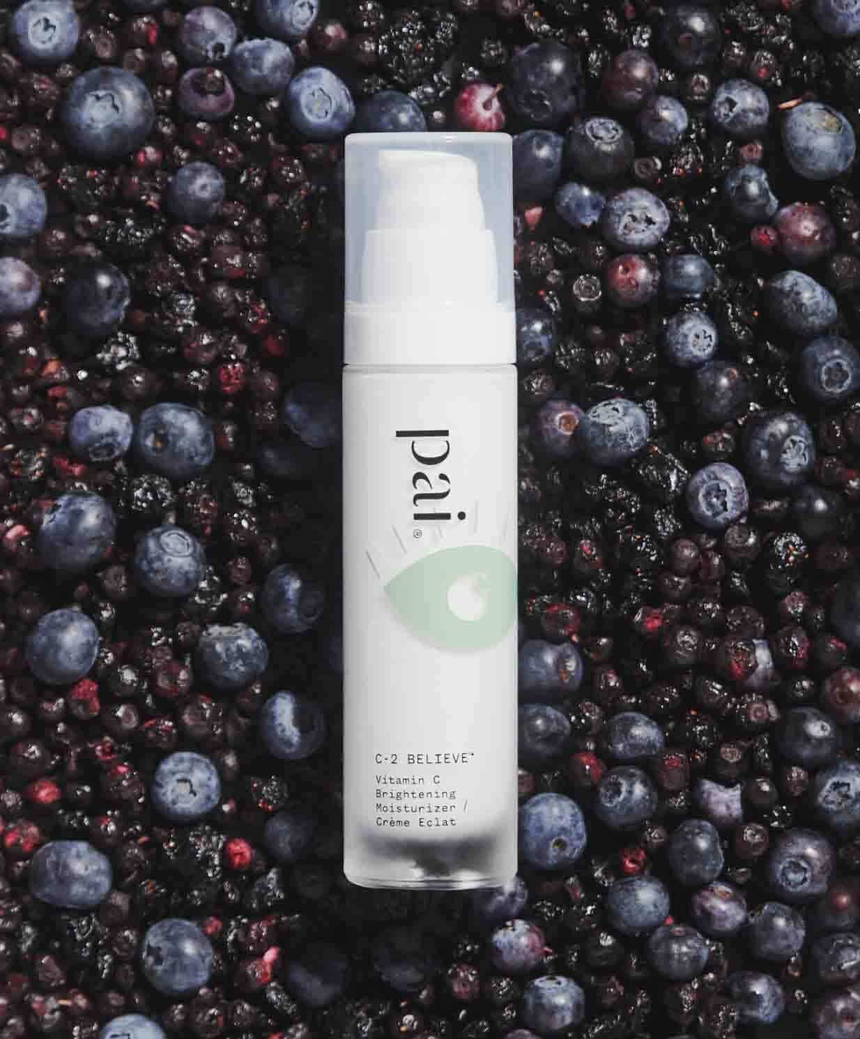 Pai C-2 Believe Vitamin C Brightening Moisturizer surrounded by fresh blueberries and pomegranate seeds