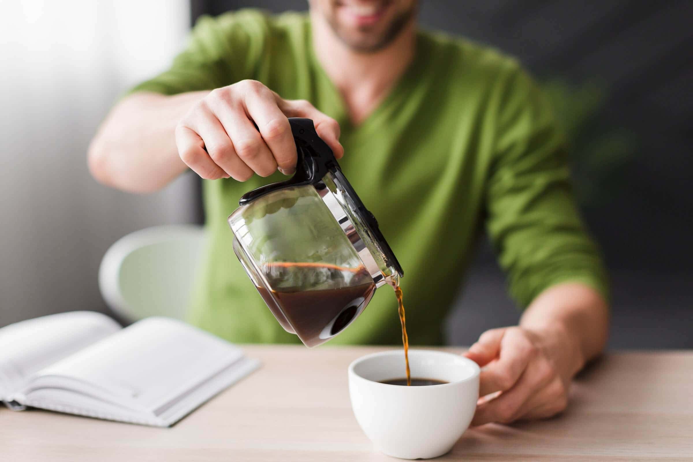 man in green shirt pouring coffee close-up