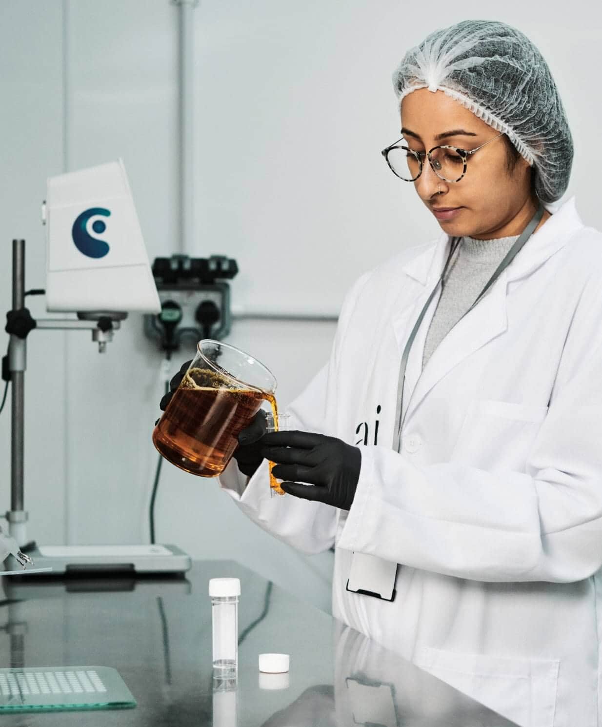 Pai Skincare scientist in laboratory examining amber liquid in glass beaker during product development