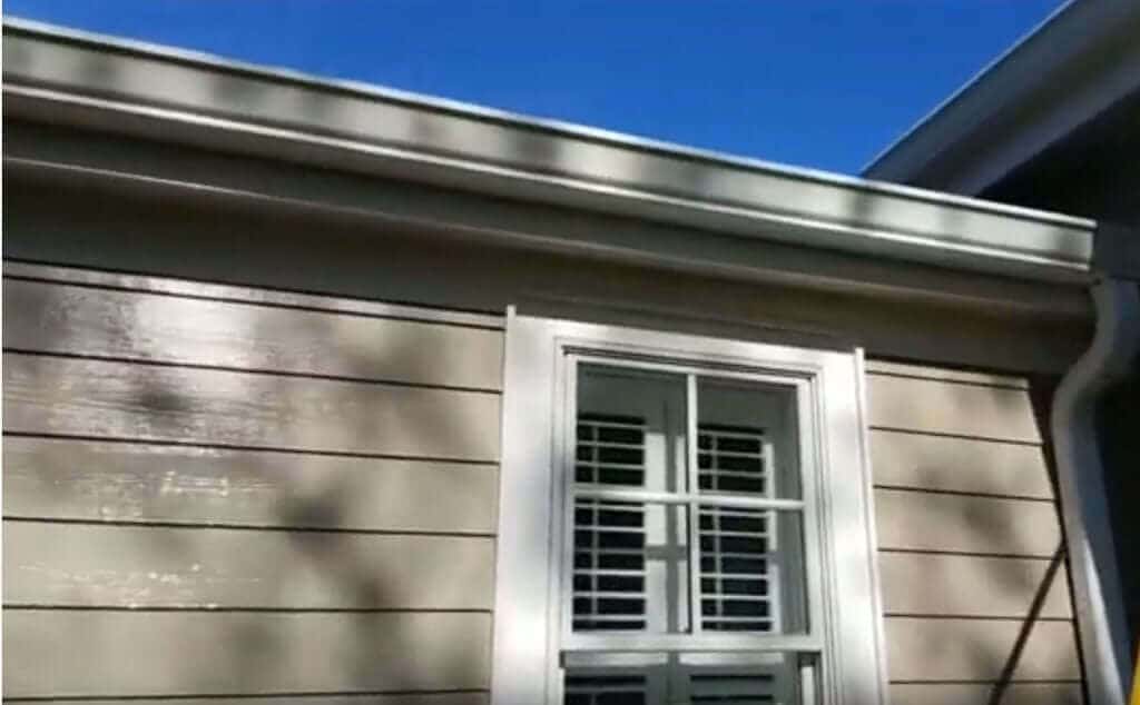 Black tiger stripes on white aluminum gutters before cleaning