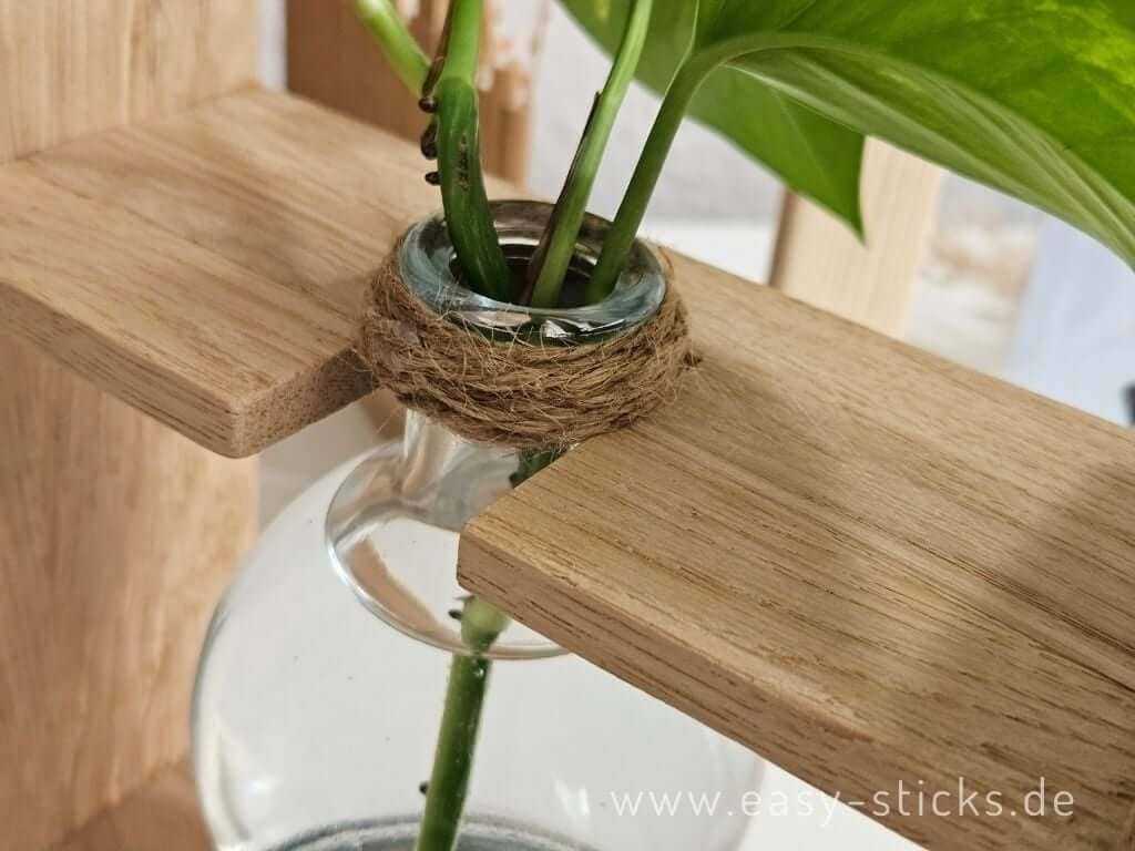 Glasflasche wird mit Jutekordel in der oberen Strebe der DIY Vermehrungsstation befestigt