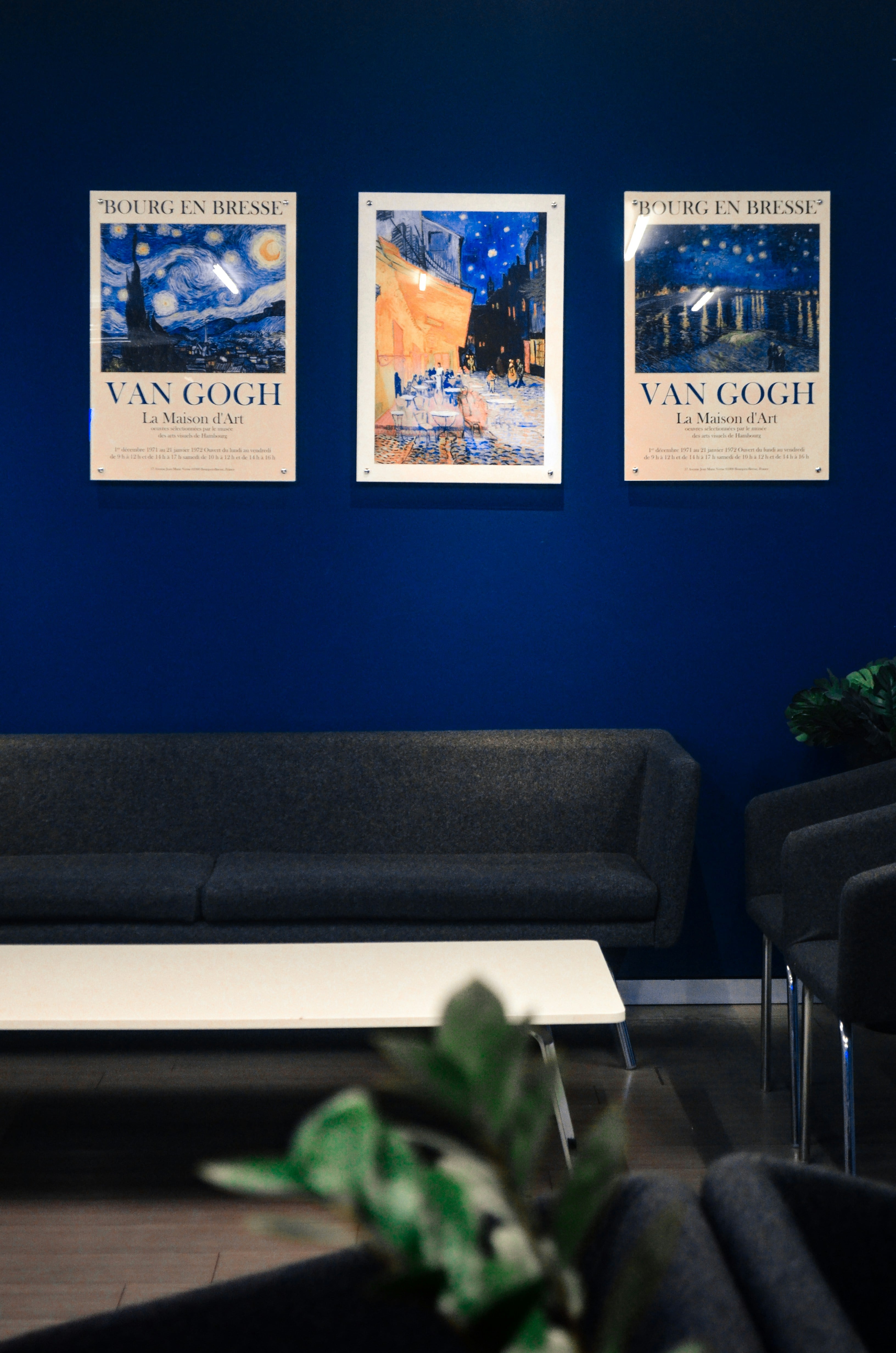 Three posters arranged above a sofa on a blue wall