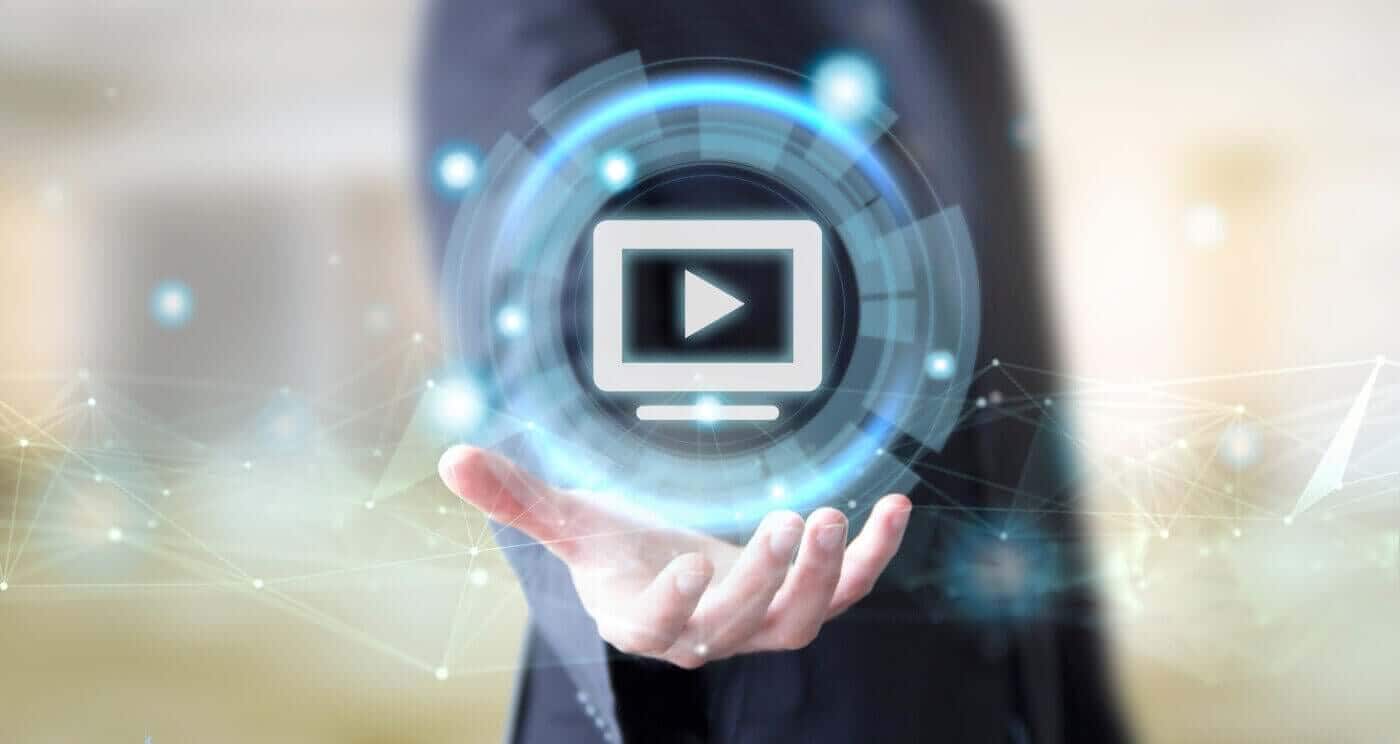 Hand holding a glowing video play icon, representing advanced technology used in video redaction services